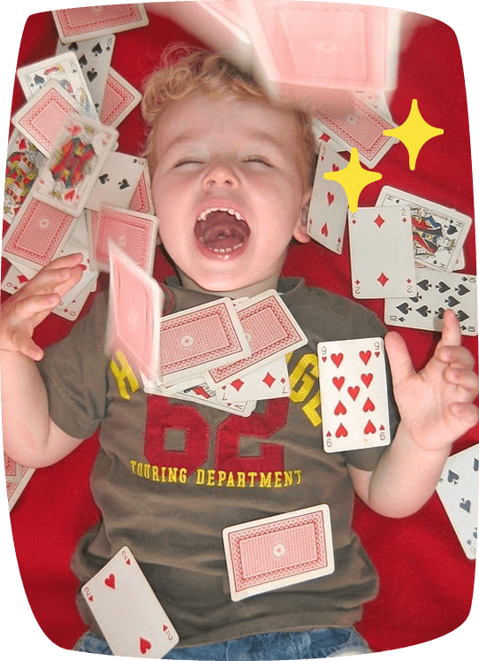 bambino a terra ride circondato da carte da gioco