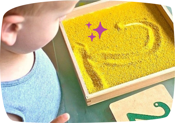 attività montessori bambno scrive il numero 2 sulla sabbia