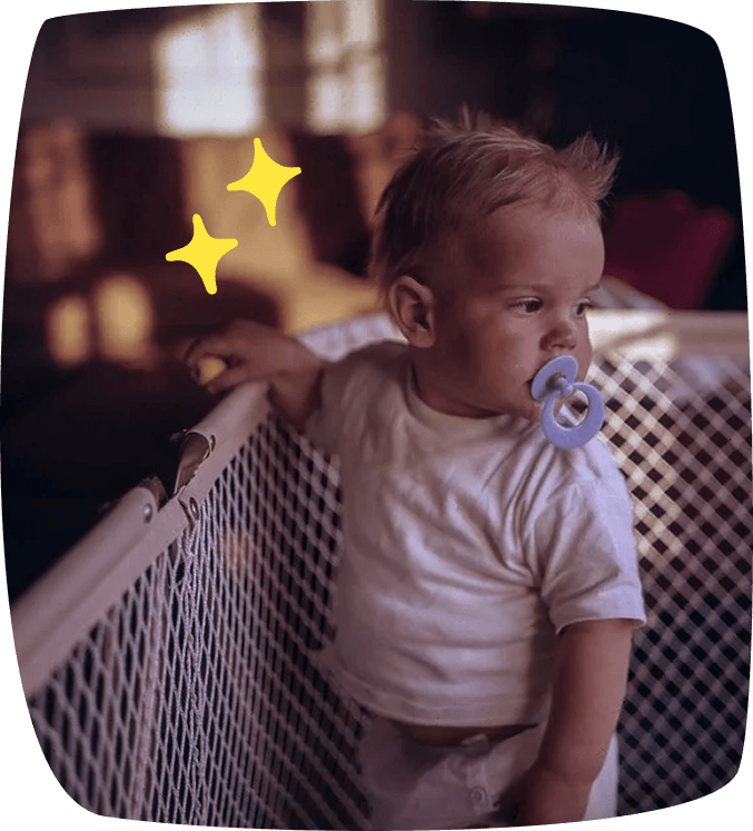bambino nel box con ciuccio in bocca
