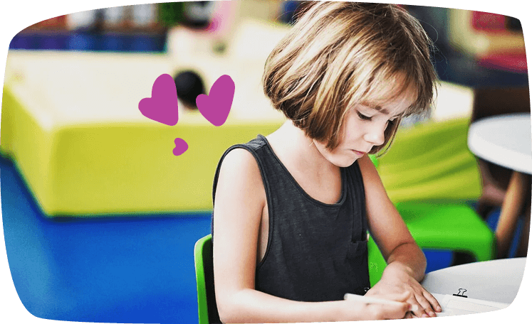 bambina seduta al tavolo scrive