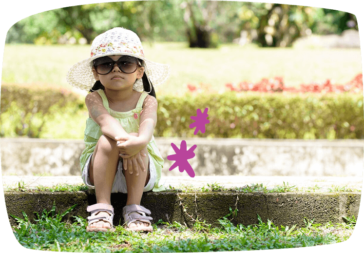 bambina seduta con occhiali e cappello da sole